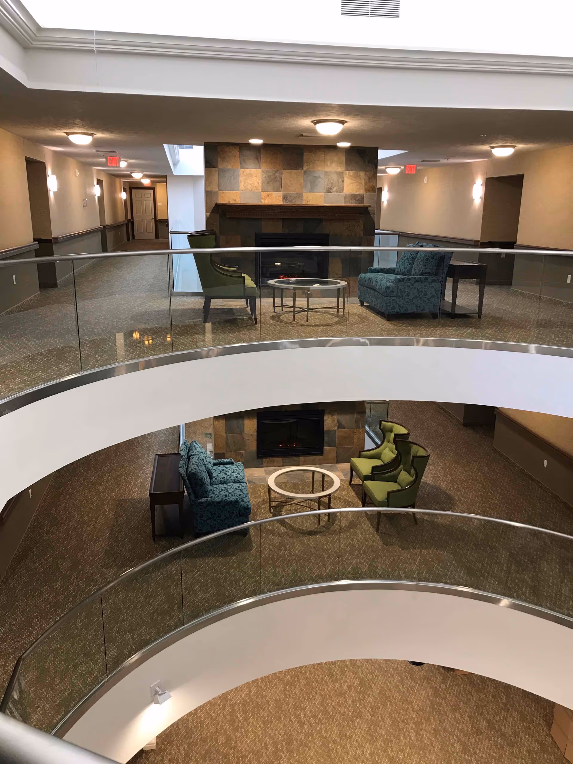 Multi-level interior atrium with curved glass railings and seating groupings and fireplaces on each floor.