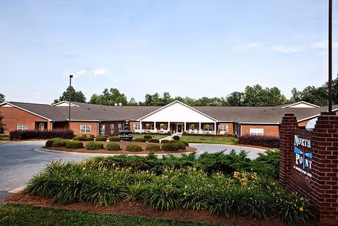 The Village of Kinston exterior: a single-story brick building with a landscaped entrance.