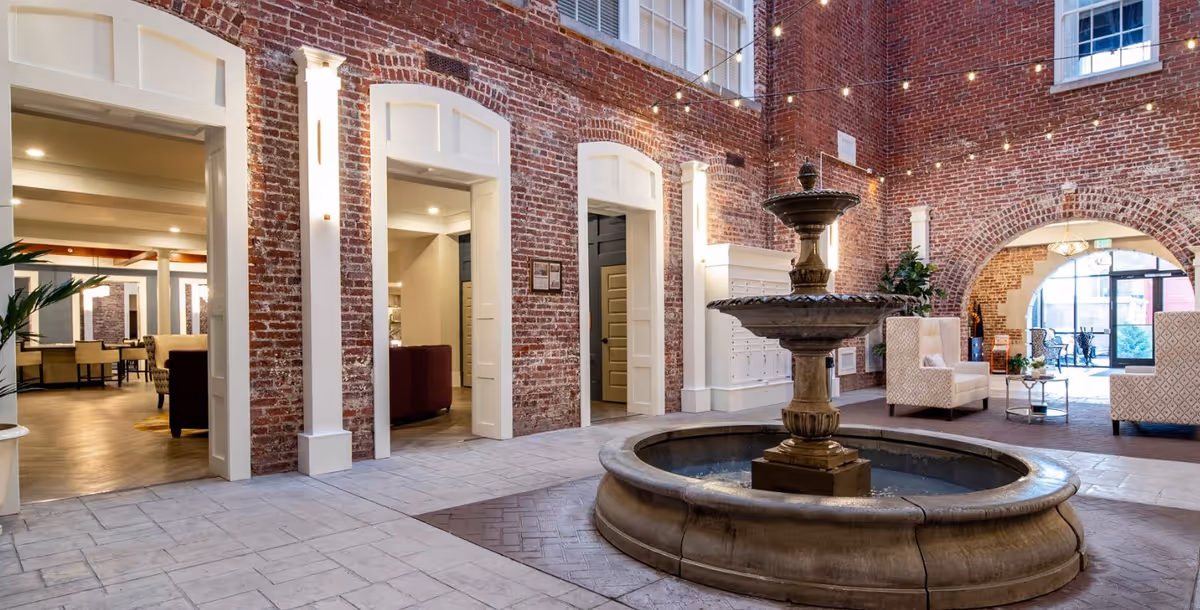 Interior view of Knoxville High Apartments featuring a decorative fountain surrounded by brick walls and seating areas.