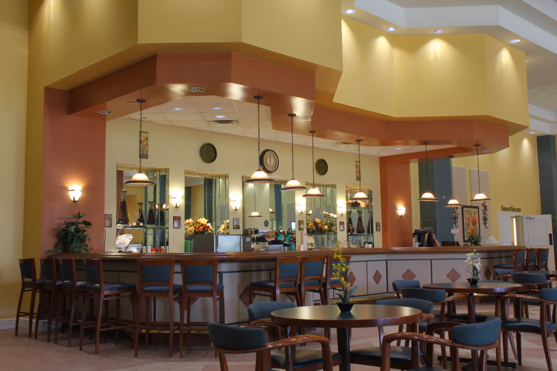 Spacious dining/lounge area with a long bar counter, hanging pendant lights and multiple round tables and chairs.