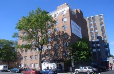 Brick mid-rise building with Madison York Assisted Living sign, trees, and street parking.