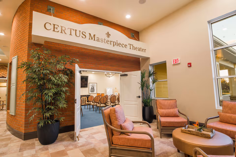 Comfortable seating area in a senior living facility lobby outside the entrance to the 'CERTUS Masterpiece Theater'.