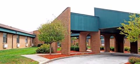 Exterior view of Crestwood Health Care Center with brick arches and green awnings.