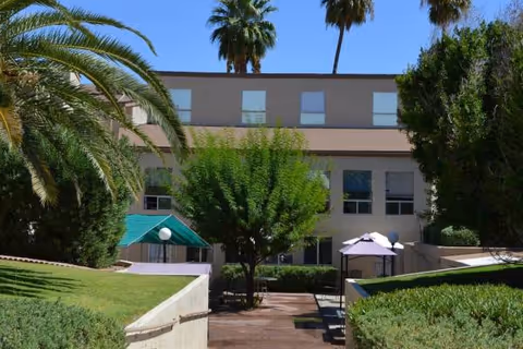 Copper Heights courtyard with trees, umbrellas, and a sunlit building in the background.