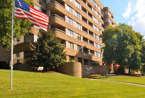 Exterior of Morningside of Belmont: flag, trees, and a brick building.