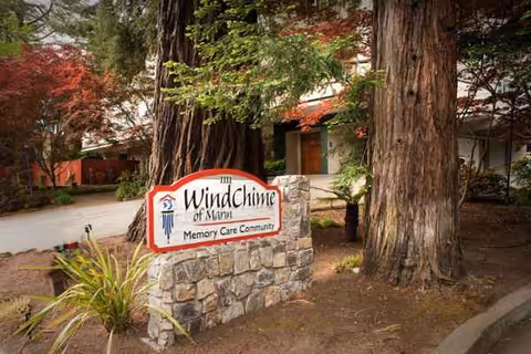 Sign for WindChime of Marin Memory Care Community in front of trees and building.