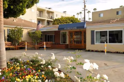 Front exterior view of Fireside Health Care Center with entrance, awning, and flowers.