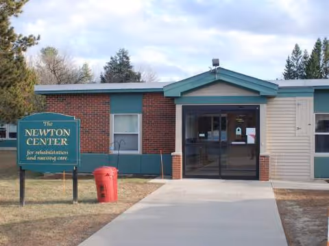 Exterior shot of The Newton Center building with a glass entrance and a sign.