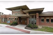 Exterior view of Daughters of Miriam Center entrance, brick building with glass doors and landscaping.