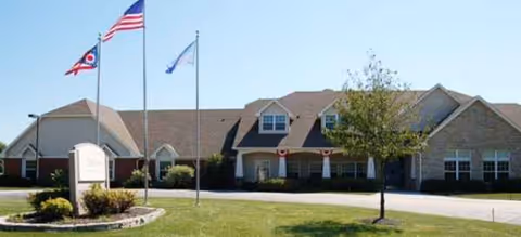 Brookdale Findlay facility exterior with flags, driveway, and manicured lawn