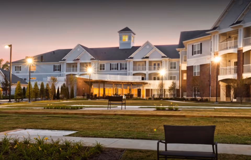 Exterior view of Irene Woods Assisted Living showcasing the building facade, entrance, and landscaped grounds at dusk.
