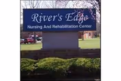 Outdoor sign for River's Edge Nursing and Rehabilitation Center with grass and bushes in the foreground and trees and buildings in the background.