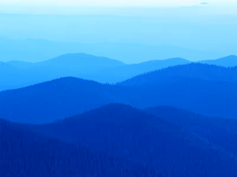 Blue-toned layered mountain ridges fading into the distance under a pale sky.