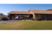 Single-story senior living building with a covered entrance/porte-cochere and a grassy lawn in front.