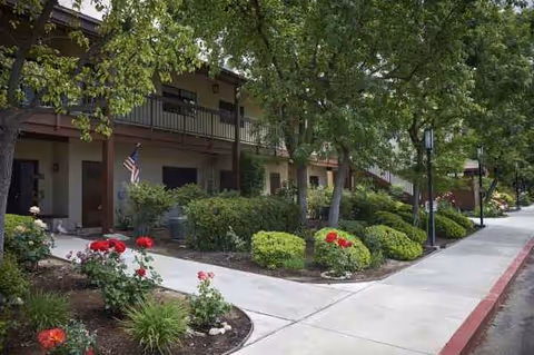 Exterior view of Health Center at Rosewood with a landscaped walkway and flowering shrubs.