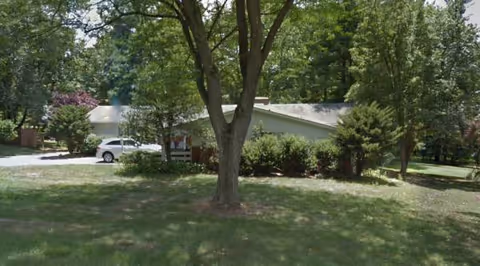 Exterior view of Chestnut Hill Manor surrounded by trees and lawn.