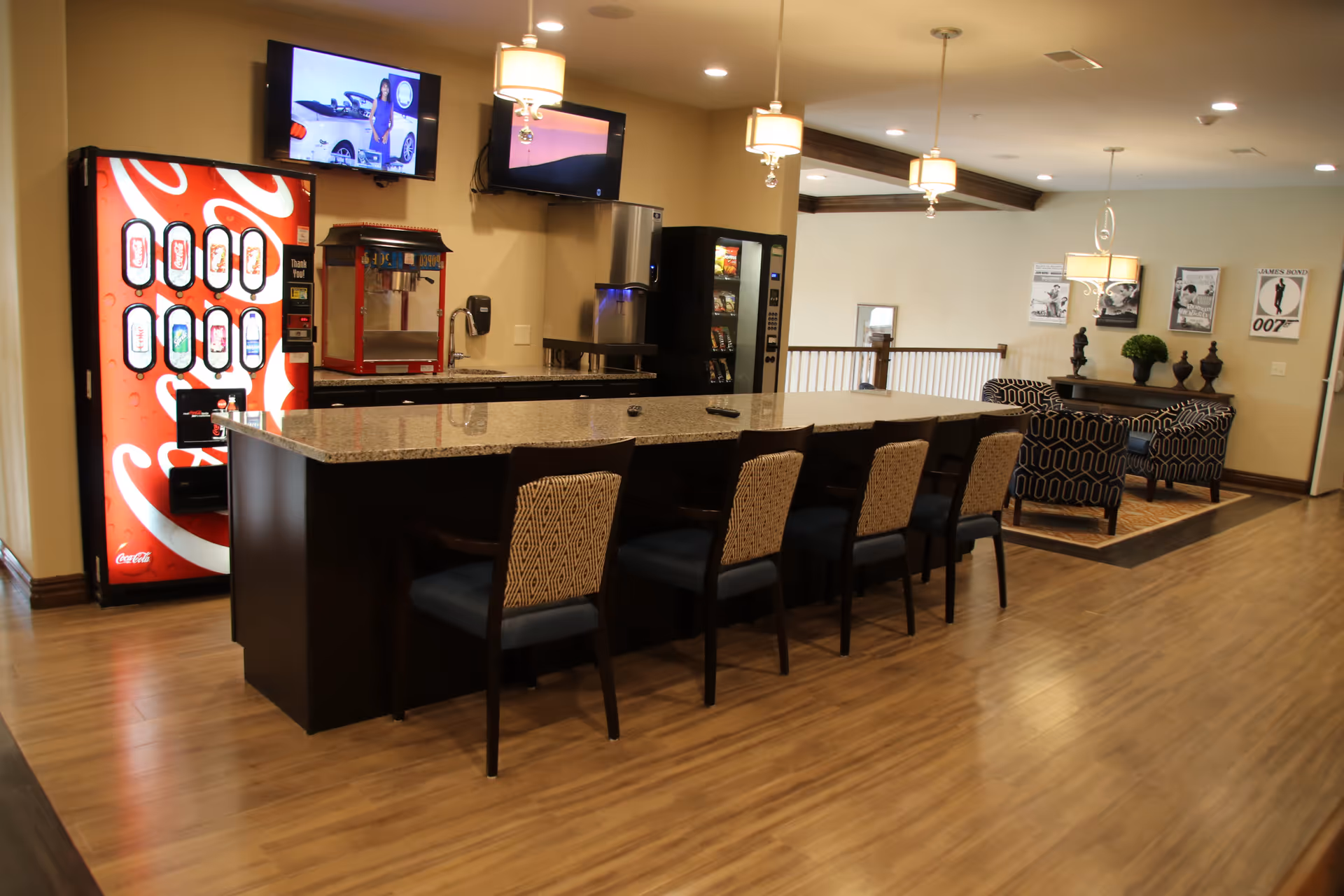 Communal lounge/dining area with a long granite-topped island, several chairs, vending machines and a seating area.