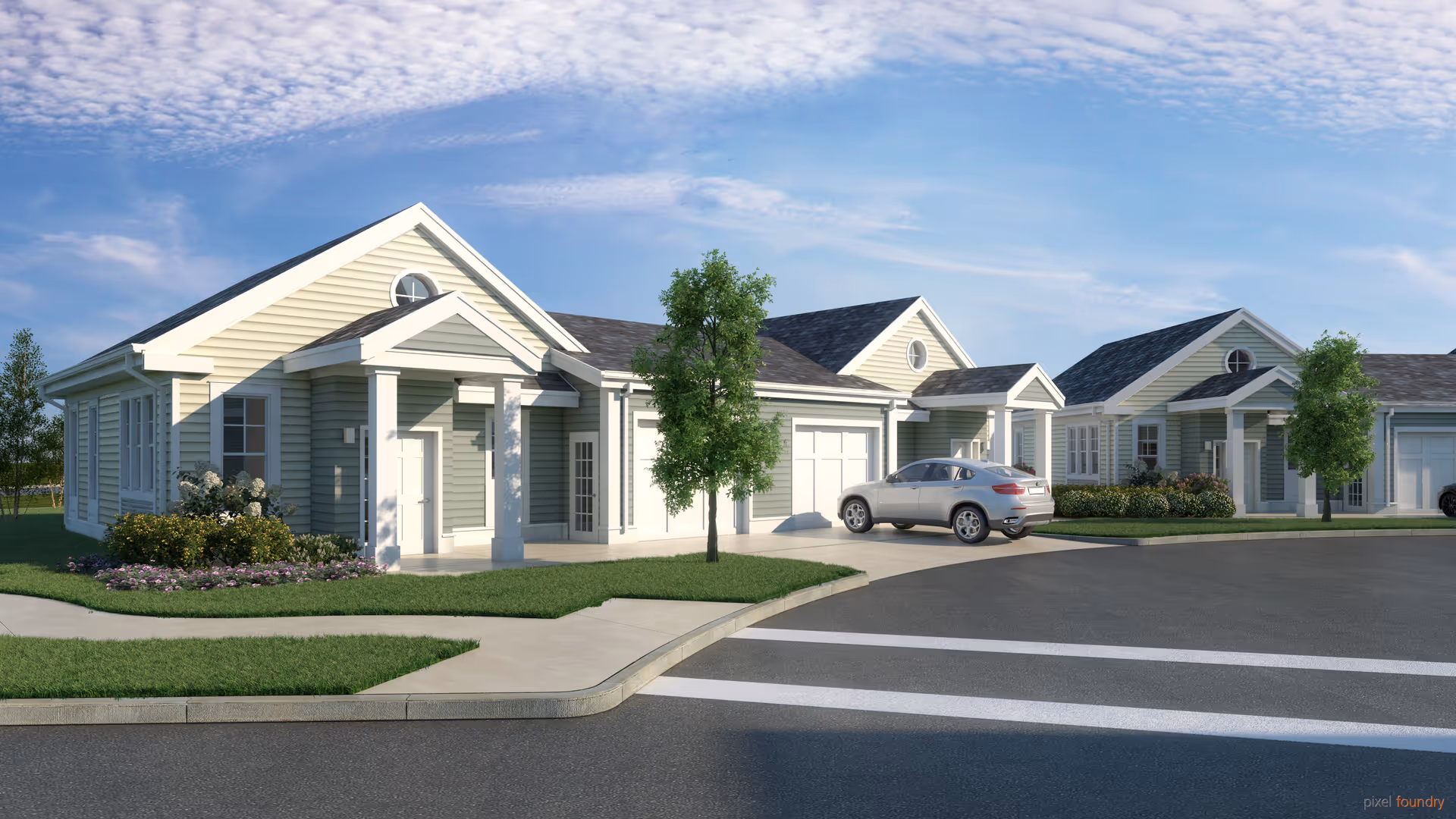 Exterior view of a residential-style senior living facility with light-colored siding, multiple units with garages, a car parked in the driveway, green lawns, trees, and a clear blue sky.