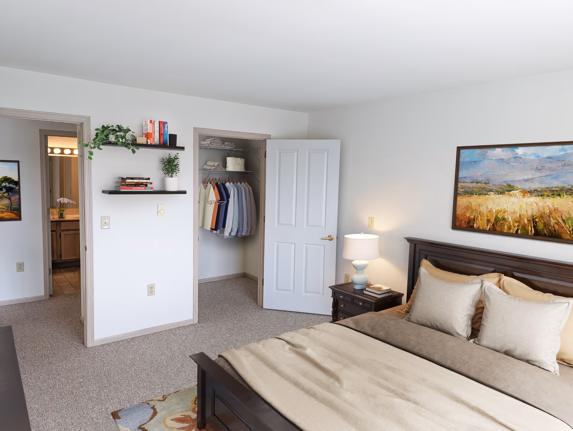 A neatly arranged bedroom in The Centennial Senior Apartments featuring a bed with beige and brown bedding, two pillows, a wooden nightstand with a lamp and books, an open closet with hanging clothes, two wall shelves with books and plants, a doorway leading to a bathroom, and a framed landscape painting on the wall.