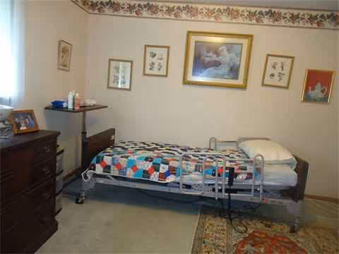 A single hospital-style bed in a cozy bedroom with framed pictures and a dresser.