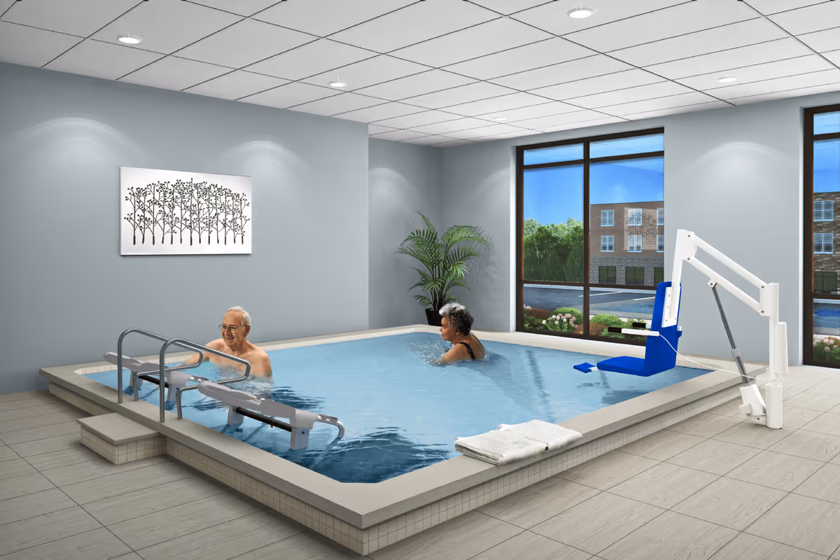 Indoor therapy pool with two older adults using a pool lift and steps in a bright room with large windows.