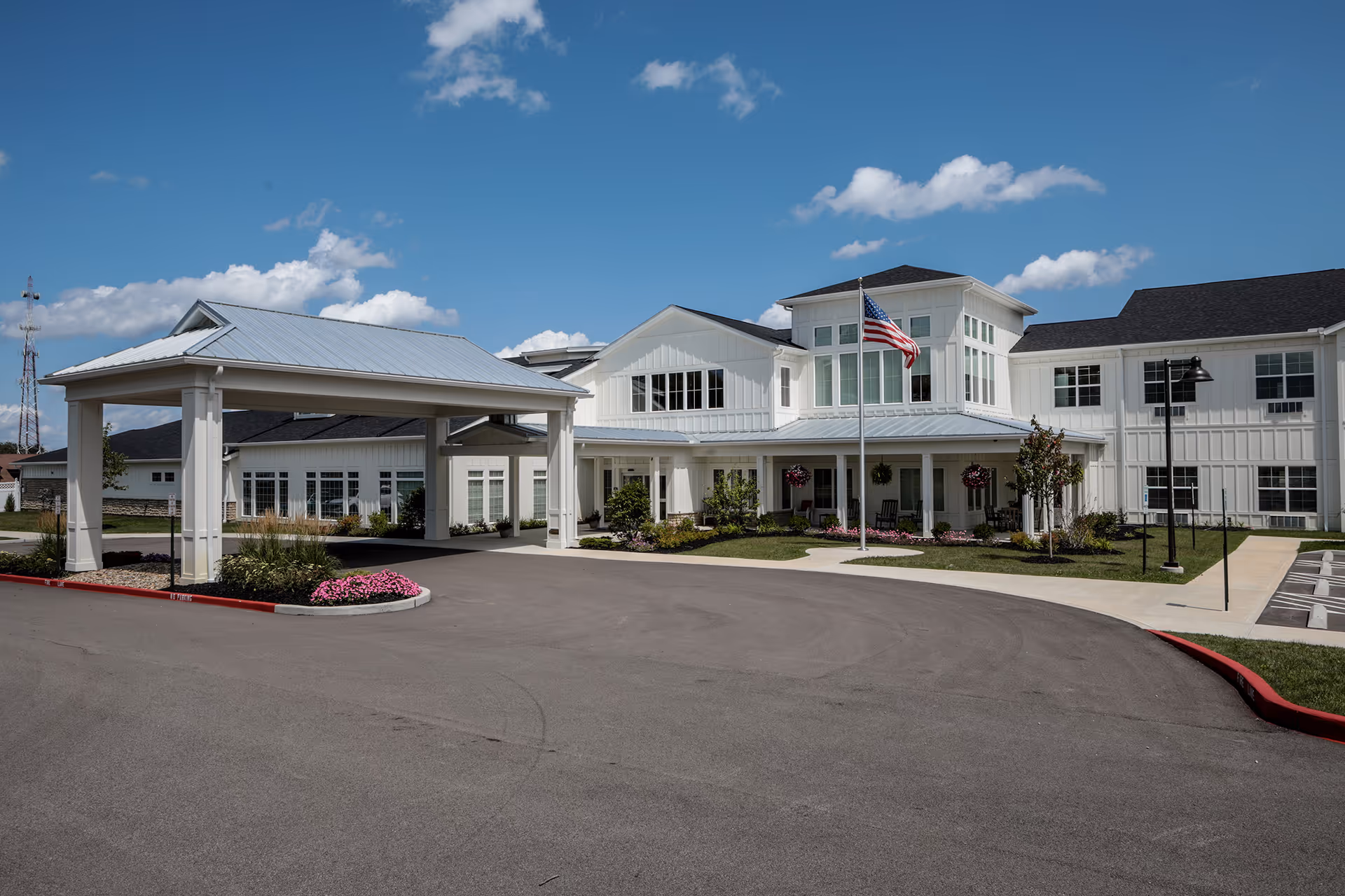 Heritage Crossing exterior showing a white modern senior living building with a covered entrance and flag.