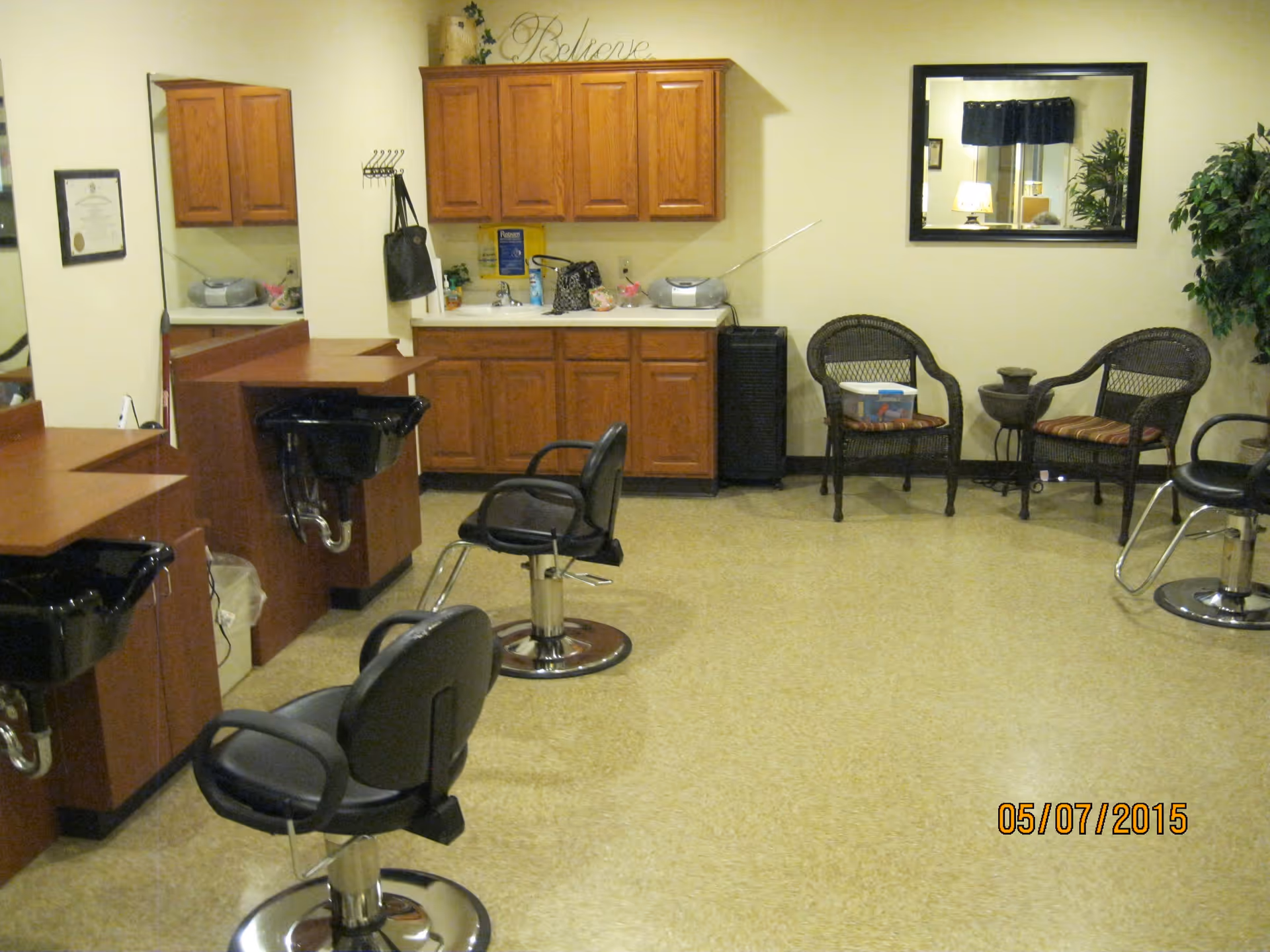 Salon area inside an assisted living facility with styling chairs, shampoo sinks, wooden cabinets, and wicker waiting chairs.