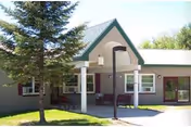 Single-story senior living facility entrance with a covered porch and benches.