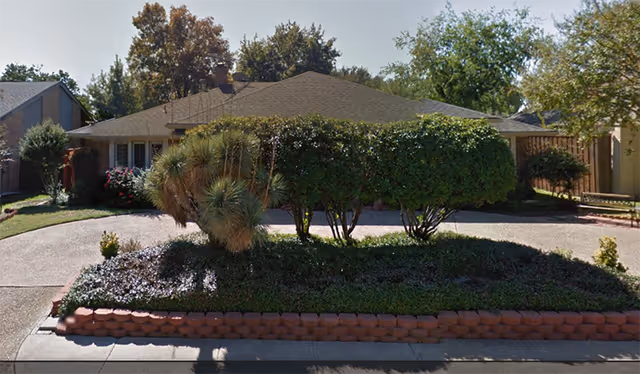 Single-story building with a landscaped front yard and trimmed shrubs along the walkway.