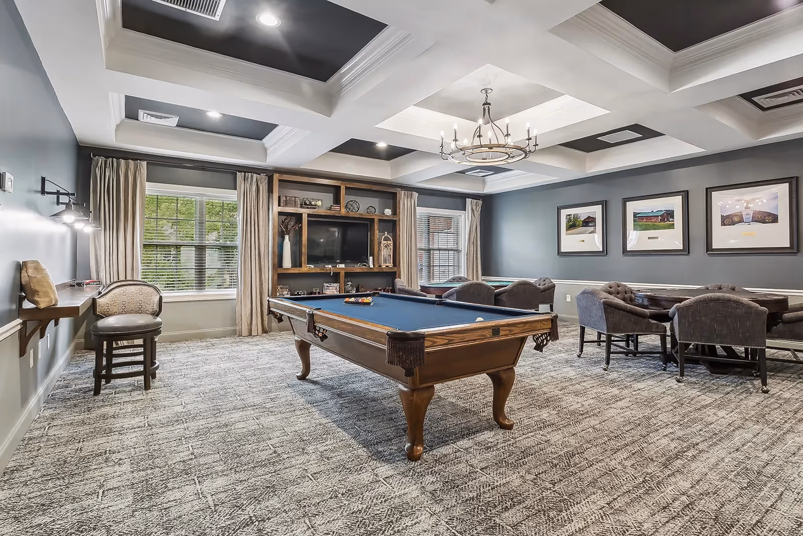 Interior recreation room with a pool table, seating area, TV and coffered ceiling.