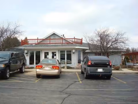 Small senior living facility front exterior with a parking lot and several cars.