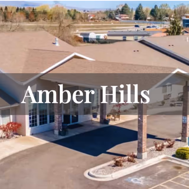 Exterior view of a senior living facility entrance with a covered drive and parking lot.