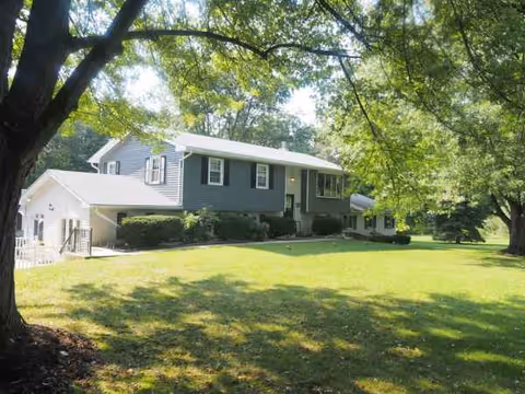 Front view of William's Manor exterior with green lawn and shaded trees.