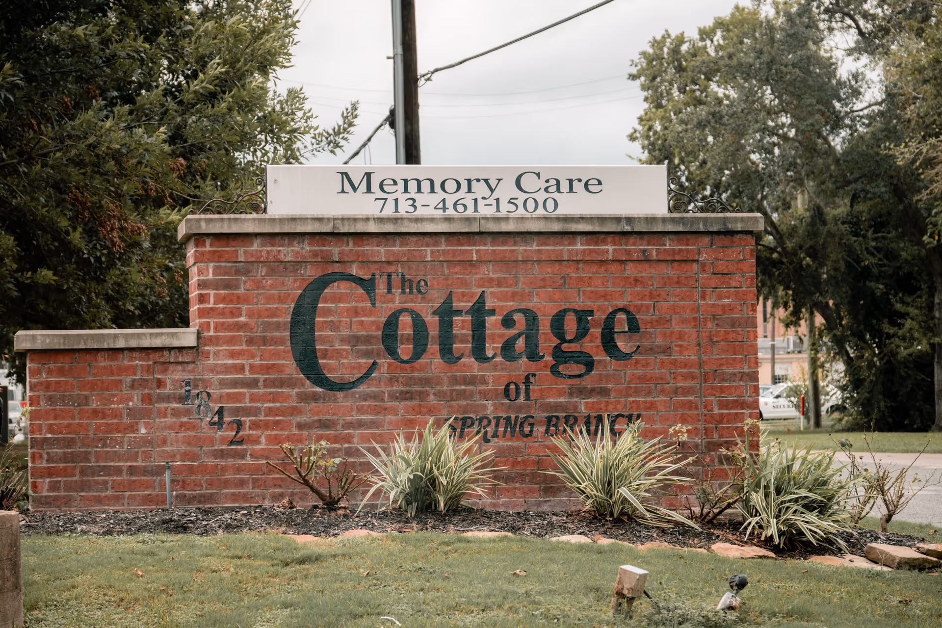 Brick entrance sign reading 'The Cottage' with a smaller 'Memory Care 713-461-1500' plaque and landscaping in front.