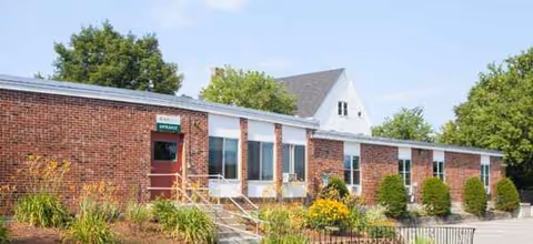 Exterior view of The Elms Center showing brick facade, entrance, and landscaped front yard.