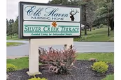 Outdoor sign for Elk Haven Nursing Home and Silver Creek Terrace Assisted Living for Independent Seniors, situated on a landscaped area with grass, bushes, and trees in the background.