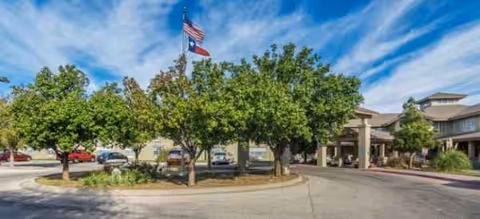 Brookdale Sherwood exterior featuring circular driveway, flag, trees, and entrance.