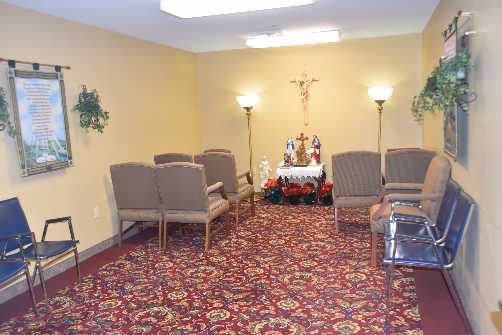 Small chapel-style sitting room with chairs arranged facing an altar displaying religious statues and a crucifix on the wall.
