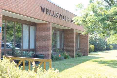 Exterior view of Wellsville Manor Care Center with brick facade and greenery.