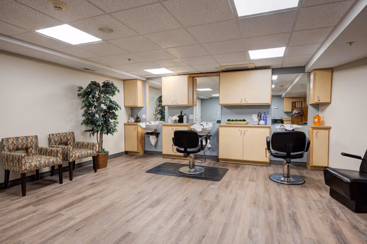 Interior salon area with barber chairs, shampoo sinks, cabinetry, and waiting chairs.