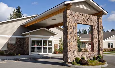 Exterior view of Regency Care Center at Monroe entrance under a stone archway.