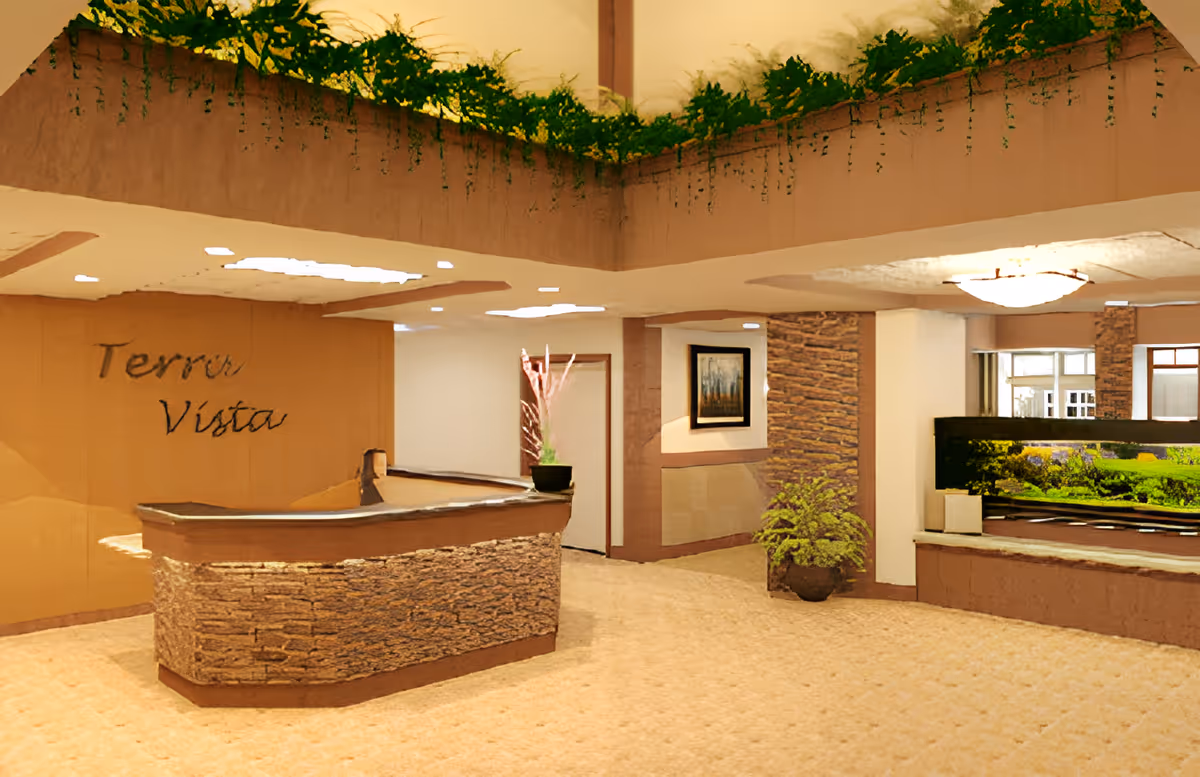 Lobby reception area with a stone-faced desk, 'Terra Vista' wall sign, potted plants and an aquarium.