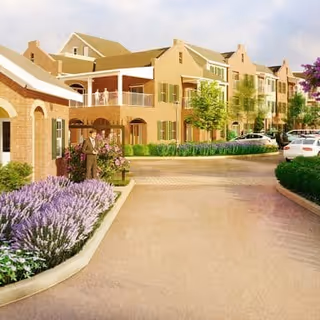 Driveway and landscaped front of a multi-story brick apartment building with balconies and a few people near the entrance.