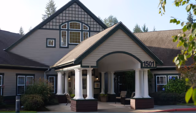 Front entrance of a senior living building with a covered portico supported by white columns and the address '1501' visible.