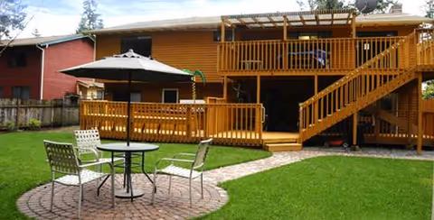 Two-story wooden facility with a large deck, umbrella, and patio seating.