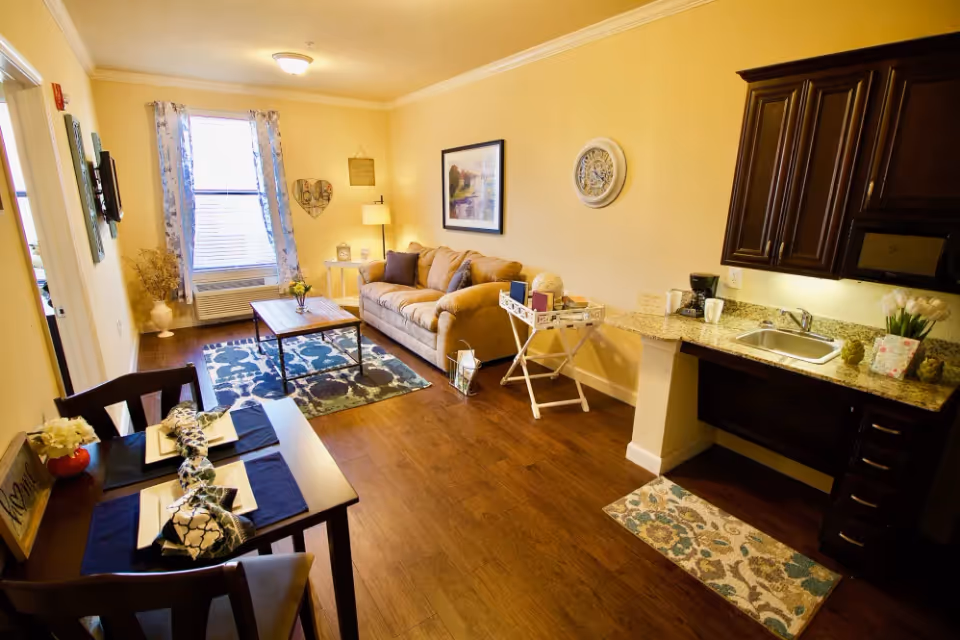 Open-plan living room and kitchenette with a sofa, coffee table, dining table, and small kitchen area.