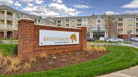Brick sign for Brightmore of South Charlotte in front of a multi-story senior living building.