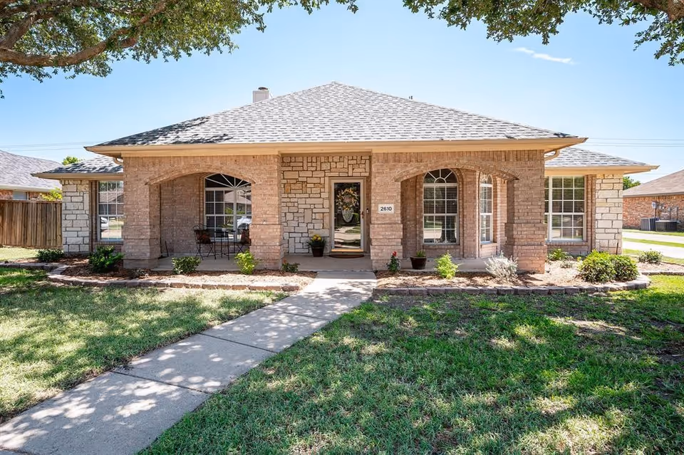 Single-story brick building with a covered front porch, centered entry door, and a walkway through a landscaped lawn.