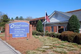 Front exterior of Carolina Gardens at Laurens with blue sign and American flag.