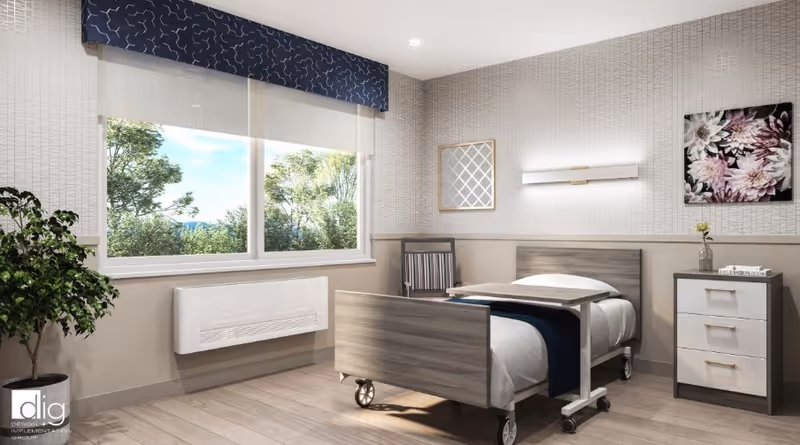 A bright and clean healthcare facility bedroom with a single hospital-style bed on wheels, a small bedside table with drawers, a chair, a potted plant near a large window showing green trees outside, and wall decorations including a framed mirror and floral artwork.